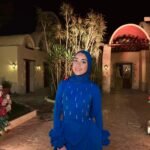 Royal blue modest evening dress with matching hijab and long train, styled with flowers and candles at outdoor venue entrance
