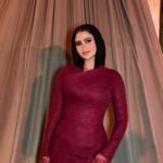 Burgundy fitted long evening dress with long sleeves under hanging floral wedding decor