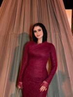 Burgundy fitted long evening dress with long sleeves under hanging floral wedding decor