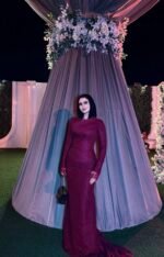 Burgundy fitted long evening dress with long sleeves under hanging floral wedding decor
