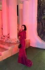 Burgundy fitted long evening dress with long sleeves under hanging floral wedding decor